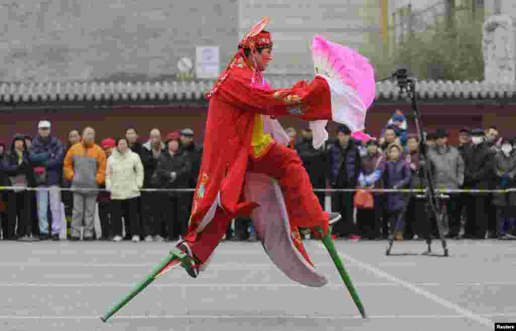Một nghệ sĩ dân gian biểu diễn đi cà kheo trong Lễ hội mùa Xuân truyền thống của Trung Quốc vào ngày mùng hai Tết tại Miếu Đông Nhạc, Bắc Kinh.