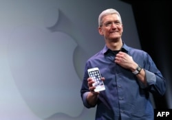 FILE - Apple CEO Tim Cook shows off the new iPhone 6 and the Apple Watch during an Apple special event at the Flint Center for the Performing Arts in Cupertino, California.