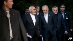 Iranian Foreign Minister Javad Zarif, left, talks with the head of the Iranian Atomic Energy Organization, Ali Akbar Salehi, while walking after an afternoon meeting with U.S. Secretary of State John Kerry and U.S. officials at the Beau Rivage Palace Hote