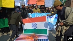 FILE - Supporters of Hafiz Saeed, head of the Pakistani religious charity Jamaat-ud-Dawa, burn representations of U.S. and Indian flags during a rally in Peshawar, Pakistan, Jan. 31, 2017. Saeed’s Jamaat-ud-Dawa is a front for Lashkar-e-Taiba. 