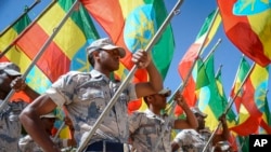 Members of the Ethiopian National Defense Force hold national flags as they parade during a ceremony to remember soldiers who died on the first day of the Tigray conflict, outside the city administration office in Addis Ababa, Ethiopia, Nov. 3, 2022. 