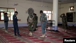 Afghan policemen inspect a mosque after a blast in Khost province, Afghanistan, May 6, 2018. 