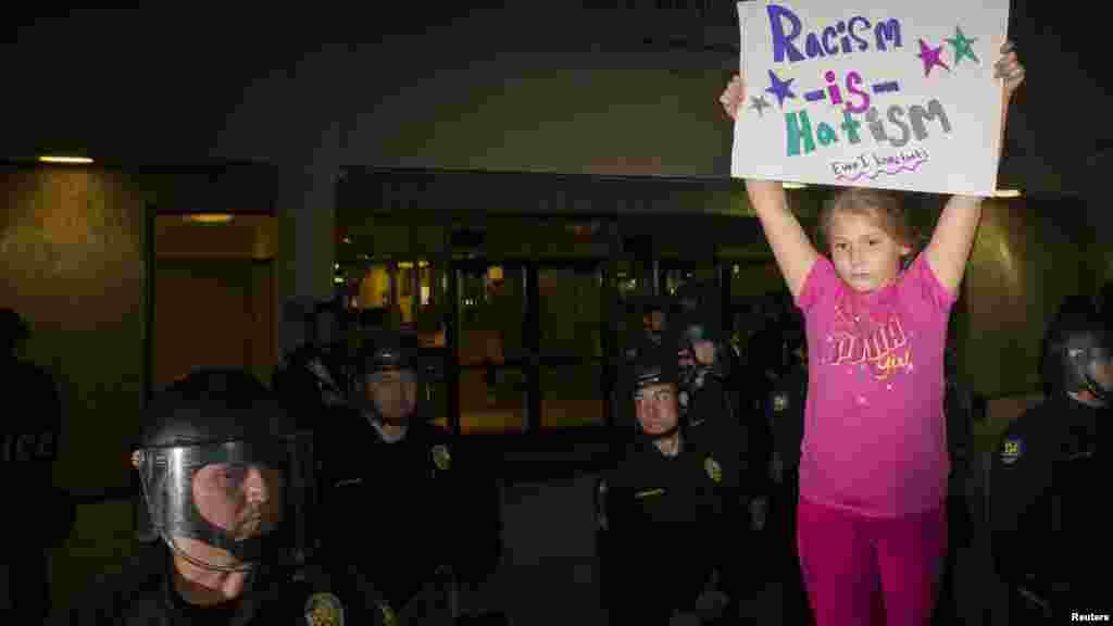 Aliyah Favela, 9, levanta um cartaz à porta da Polícia de Phoenix, uma semana depois de um homem desarmado ter sido baleado mortalmente pela polícia. Phoenix, Arizona, Dez. 8, 2014.