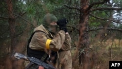 A Ukrainian border guard scouts with a monocular near the Ukrainian border with Russia and Belarus, Nov. 3, 2022.