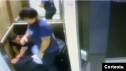 Captura de pantalla del video donde se ve al periodista Juan Fernando Barona agrediendo a una mujer, que se encuentra tendida en el piso de en un ascensor, bajo la mirada de otro hombre.