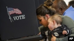 新墨西哥州選民米蘭達·帕迪拉抱著11個月大的兒子投下選票。 (2022年11月8日)