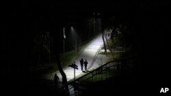 People walk in a park during a blackout in Kyiv, Ukraine, Nov. 6, 2022. 