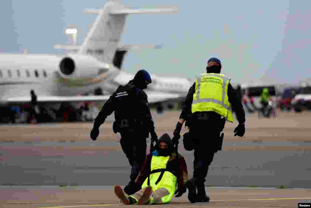 Police officers detain a climate activist during a protest against environmental pollution from aviation, at Amsterdam's Schiphol Airport, in Schiphol, Netherlands, Nov. 5, 2022.