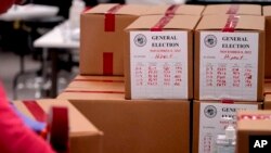 Seorang petugas tempat pemungutan suara tampak menyegel kotak berisi surat suara pemilu paruh waktu di kantor pencatatan Maricopa County, di Phoenix, Arizona, pada 9 November 2022. (Foto: AP/Matt York)