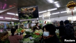 FILE - People shop for vegetables at a market in Beijing, Jan. 15, 2021.