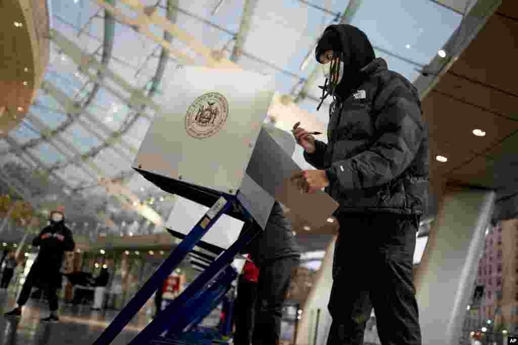 The first voters of the day begin filling out their ballots at a polling site in the Brooklyn Museum as the doors open for the midterm election, Nov. 8, 2022, in the Brooklyn borough of New York.