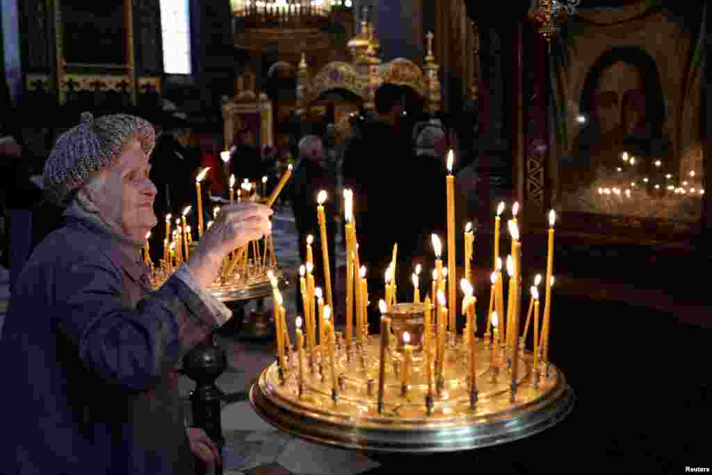Украински православни верници палат свеќи за време на неделната миса во катедралата Свети Володимир во Киев, Украина.
