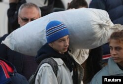 FILE - A boy carries a sack as civilians evacuated from the Russian-controlled Kherson region of Ukraine arrive at a local railway station, after Russian-installed officials extended an evacuation order to the area along the eastern bank of the Dnipro River, in the town of Dzhankoi, Crimea, Nov. 2, 2022.