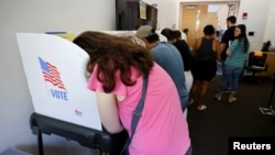 FILE - A voter leans into a booth while filling out her ballot form during midterm elections in Chapel Hill, North Carolina, Nov. 5, 2022.