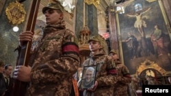Ukrainian servicemen carry a portrait and a coffin with the body of their comrade Taras Havrylyshyn, who was recently killed in a battle against Russian troops, during a funeral ceremony in Lviv, Nov. 9, 2022. 