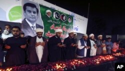 Members of the Shiite Ulema Council pray during a candlelight vigil in Karachi, Pakistan, Oct. 29, 2022, for Pakistani journalist Arshad Sharif, who was killed earlier in the month in Nairobi, Kenya.