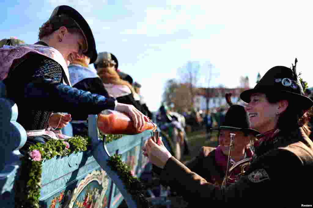 Farmers&#39; wives, dressed in traditional Bavarian costumes, give out schnapps from a wooden carriage, to the people on the way to the chapel on the Kalvarienberg during the Leonhardi Ritt procession, to pray to St. Leonhard, the patron saint of animals, in Bad Toelz, Germany.