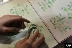 Seorang pengunjung sedang mencoba menulis huruf China dengan stempel saat berlangsungnya pameran di Taipei, Taiwan, 20 Oktober 2017. (SAM YEH / AFP)