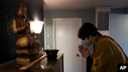 Resident priest Genmyo Jana Zeedyk bows before a Buddha statue during a Sunday practice at the Anchorage Zen Community in Anchorage, Alaska, Oct. 9, 2022. (AP Photo/Jae C. Hong)