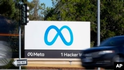 FILE - A car passes Facebook's new Meta logo on a sign at the company headquarters on Oct. 28, 2021, in Menlo Park, Calif. Facebook parent Meta is laying off 13% of its employees as it contends with faltering revenue and broader tech industry woes. 