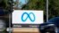 FILE - A car passes Facebook's new Meta logo on a sign at the company headquarters on Oct. 28, 2021, in Menlo Park, Calif. Facebook parent Meta is laying off 13% of its employees as it contends with faltering revenue and broader tech industry woes. 