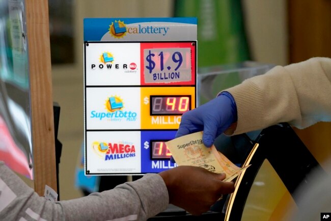 A customer is handed Powerball tickets purchased at Lichine's Liquor & Deli in Sacramento, Calif., Monday, Nov. 7, 2022. Monday night's drawing is estimated to be a record $1.9 billion. (AP Photo/Rich Pedroncelli)