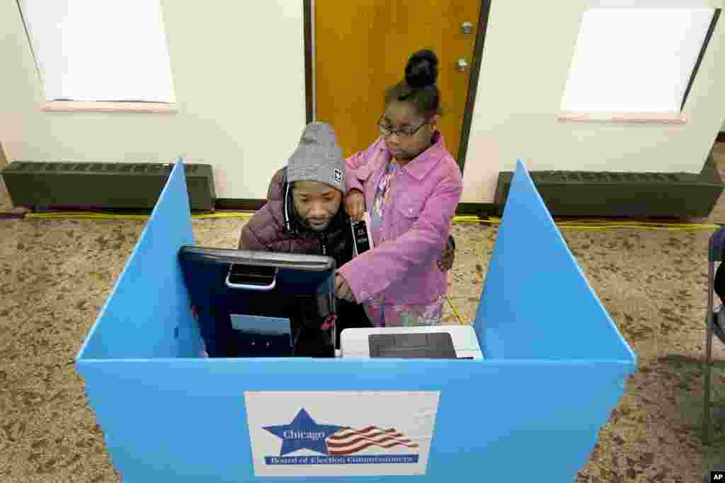 Christopher Sandridge teaches his daughter Christina the voting process as he casts a ballot at the Rev. Dr. Martin Luther King Community Center on the Southside of Chicago, Nov. 8, 2022.