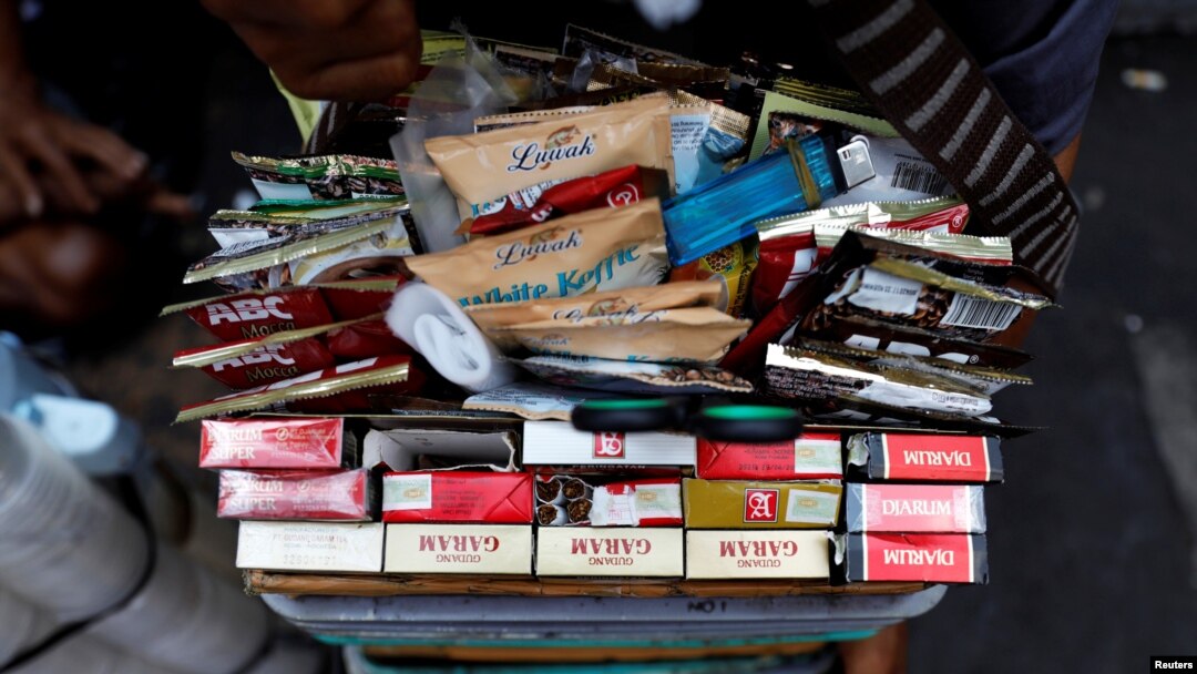 Berbagai merek rokok dipajang di antara minuman sachet di ember seorang pedagang kaki lima di pasar tradisional di Jakarta, 31 Mei 2019. (REUTERS/Willy Kurniawan)