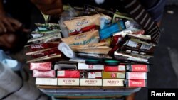Berbagai merek rokok dipajang di antara minuman sachet di ember seorang pedagang kaki lima di pasar tradisional di Jakarta, 31 Mei 2019. (REUTERS/Willy Kurniawan)