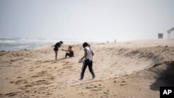 A few people put up with strong wind on the beach in Palm Beach, Fla., Nov. 8, 2022, as Tropical Storm Nicole continues to increase in strength and is expected to make landfall along Florida's east coast early Thursday.