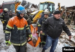 Rescuers evacuate the body of a local resident at the site where a house was destroyed in a Russian missile strike in the town of Zmiiv in Kharkiv region, Ukraine, Jan. 8, 2024.