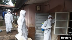 A burial team wearing protective clothing prepare to enter the home a person suspected of having died of the Ebola virus, in Freetown, September 28, 2014.