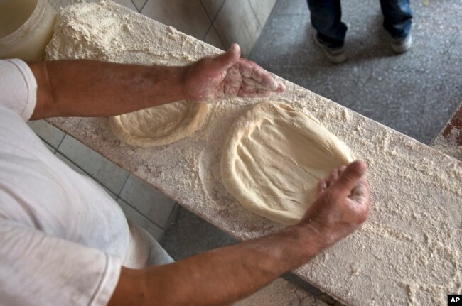 Bakers prepare the dough with ingredients provided by families to prepare and bake special pitta bread called in Albanian (pitalka) for Iftar during the holy month of Ramadan in southern Kosovo city of Prizren on Friday, June 17, 2016. (AP Photo)