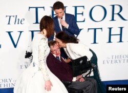 Jane Wilde Hawking (tengah) mencium mantan suaminya, ahli fisika Stephen Hawking, pada pemutaran perdana di Inggris film "The Theory of Everything" yang diambil dari kisah hidup Stephen Hawking, di London, 9 Desember 2014. Aktor Eddie Redmayne, yang memerankan Hawking, menemani.