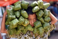 Seorang anak lelaki membawa ketupat untuk dijual di sebuah pasar di Makassar, Sulawesi Selatan, 1 November 2005 untuk merayakan Idul Fitri, yang menandai akhir bulan suci Ramadhan. (Foto: Reuters/Yusuf Ahmad)