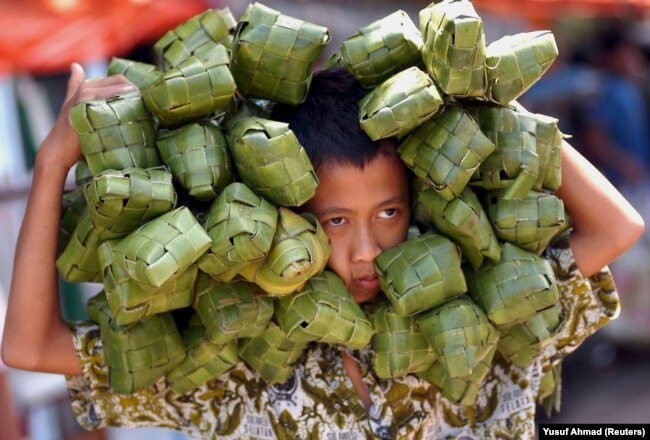 Seorang anak lelaki membawa ketupat untuk dijual di sebuah pasar di Makassar, Sulawesi Selatan, 1 November 2005 untuk merayakan Idul Fitri, yang menandai akhir bulan suci Ramadhan. (Foto: Reuters/Yusuf Ahmad)