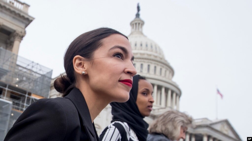 FILE - Rep. Alexandria Ocasio-Cortez, left, and D-N.Y., Rep. Ilhan Omar, D-Minn., center, walk down the House steps to take a group photograph of the House Democratic women members of the 116th Congress on the East Front Capitol Plaza on Capitol Hill.