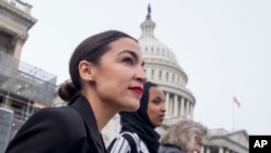 FILE - Rep. Alexandria Ocasio-Cortez, left, and D-N.Y., Rep. Ilhan Omar, D-Minn., center, walk down the House steps to take a group photograph of the House Democratic women members of the 116th Congress on the East Front Capitol Plaza on Capitol Hill.
