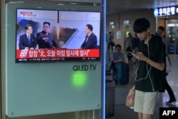A youth walks past a television screen showing a file image of North Korean leader Kim Jong Un as news anchors provide coverage of a North Korean missile launch, at a railway station in Seoul, Aug. 26, 2017.