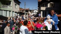 Seorang pria Muslim Bulgaria menggendong putranya di atas kuda saat mereka menghadiri ritual menjelang upacara sunat massal di Desa Ribnovo, Bulgaria, 11 April 2021. (Foto: REUTERS/Stoyan Nenov)