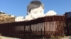 Erigen imagen gigante de niño que se asoma por muro EE.UU.-México 