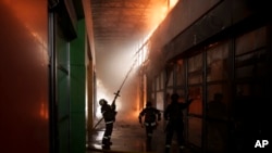 Firefighters work to extinguish a fire at a shop following a Russian bombardment in Kharkiv, Ukraine, April 22, 2022.
