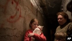 Elizabeth, 12, berlindung bersama kucing dan keluarganya di ruang bawah tanah di sebuah apartemen di Lyman, Ukraina, pada 26 April 2022. (Foto: AP/Leo Correa)