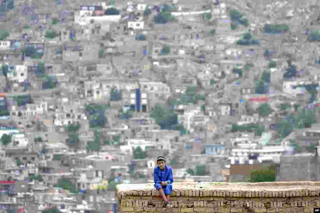 Seorang bocah laki-laki duduk di atas atap rumahnya di Kabul, Afghanistan.