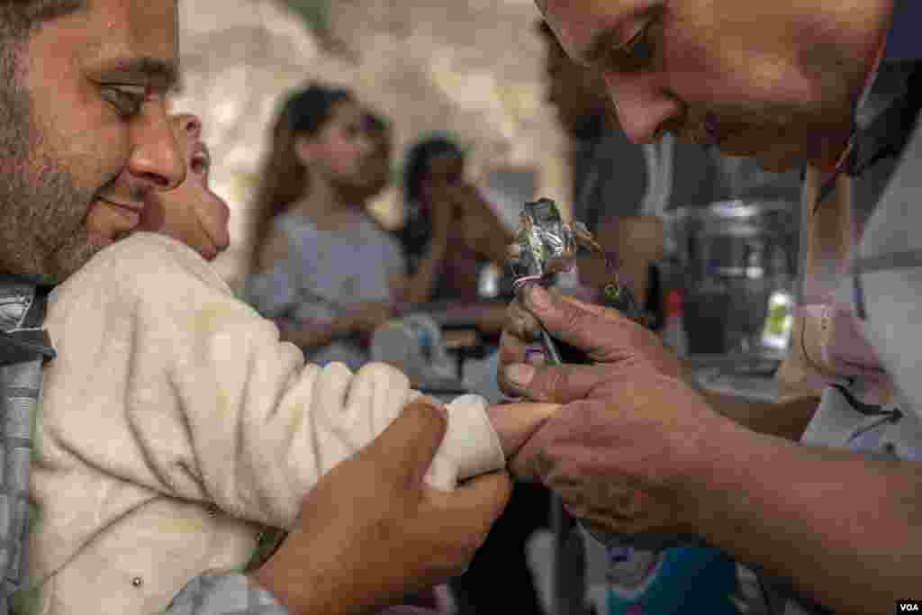 A Christian child's right wrist is tattooed with a traditional Coptic cross at the Church of Saint Samaan the Tanner, in Cairo, April 17, 2022. (H. Elrasam/VOA)