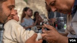 Uma criança é tatuada numa cerimónia religiosa na Igreja Copta de Saint Samaan de Tanner, Cairo, Egipto, 17 Abril 2022 (H. Elrasam/VOA)

