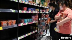 Warga Beijing, China berbelanja makanan dan kebutuhan sehari-hari di sebuah supermarket, di antara rak-rak makanan yang mulai kosong akibat diserbu warga yang menimbun makanan dan kebutuhan harian lainnya. 