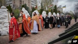 Orthodox priests hold a ceremony to honor Chernobyl firefighters to mark the 36th anniversary of the Chernobyl nuclear disaster in the capital Kyiv, Ukraine, April 26, 2022. Firefighters sculptures are covered with bags to protect against the Russian shelling.