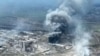 Video handout yang diambil dari rekaman yang dirilis oleh Dewan Kota Mariupol, 19 April 2022 menunjukkan awan asap mengepul di atas pabrik baja Azovstal dan gerbang galangan kapal Azov yang hancur akibat serangan udara Rusia. (Handout / Dewan Kota Mariupol / AFP)