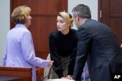 Aktris Amber Heard berbicara dengan pengacaranya di ruang sidang di Fairfax County Circuit Courthouse di Fairfax, Virginia, 25 April 2022. (Foto: AP)